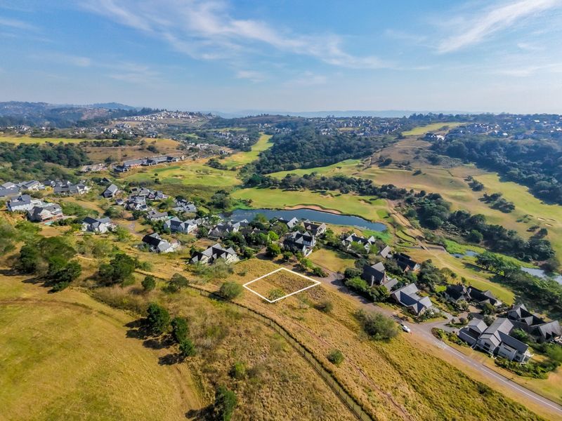 Aerial view of a vacant residential land plot situated within a scenic estate, featuring surrounding green belts and established residential properties.
