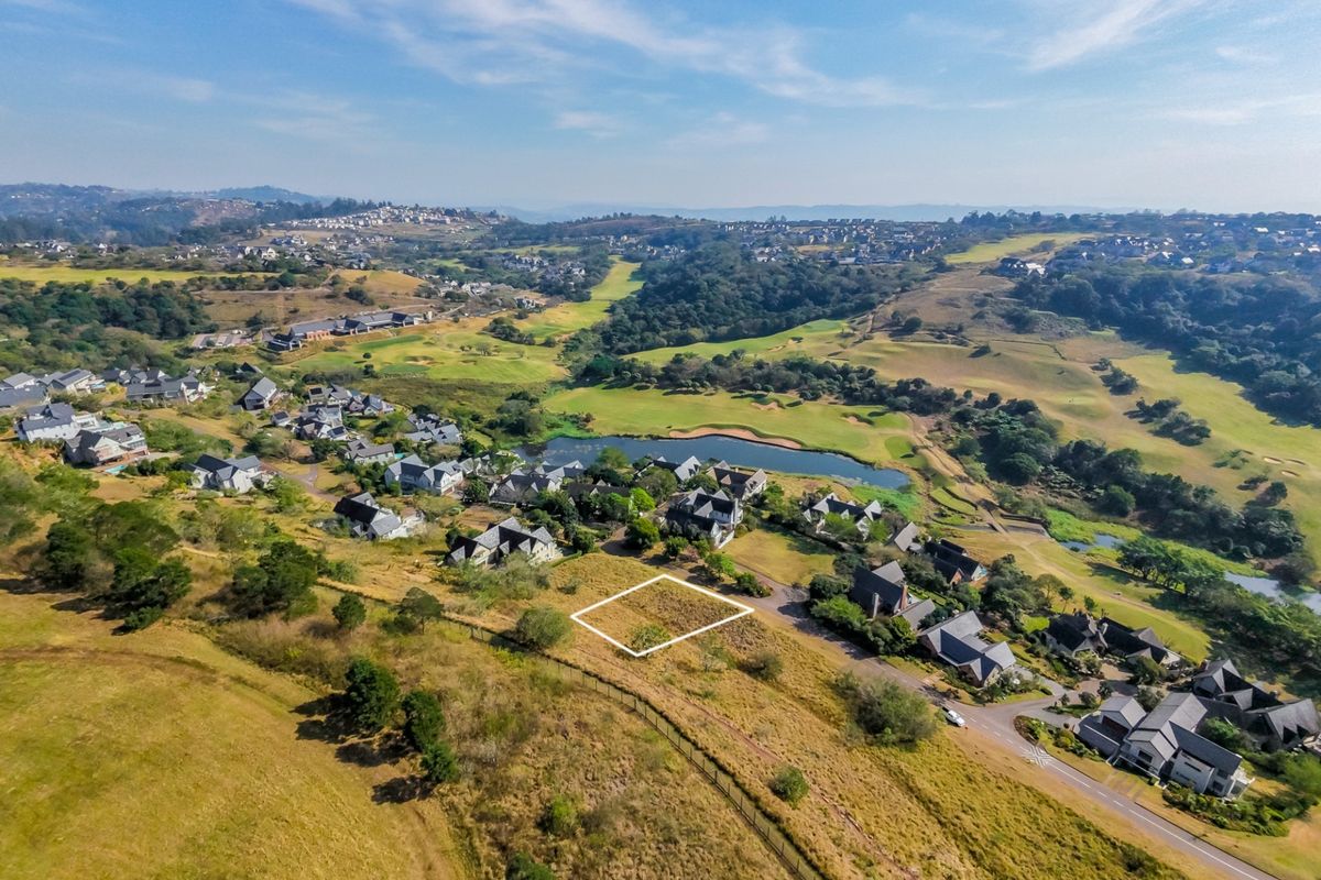 Aerial view of a vacant residential land plot situated within a scenic estate, featuring surrounding green belts and established residential properties.