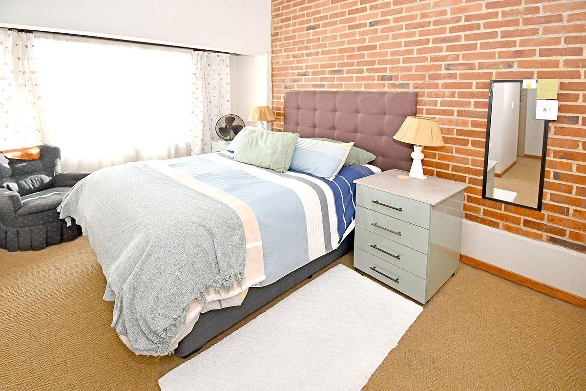 A bedroom featuring an exposed brick feature wall and carpeted flooring, offering a warm and textured aesthetic.
