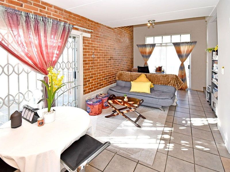 Open plan living area featuring an exposed brick wall, tiled flooring, and sliding glass doors providing access to the exterior.