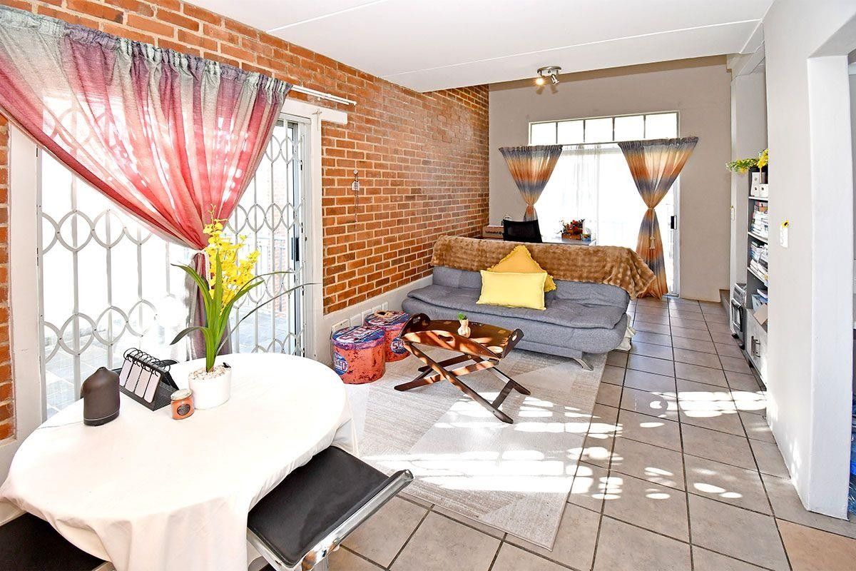 Open plan living area featuring an exposed brick wall, tiled flooring, and sliding glass doors providing access to the exterior.