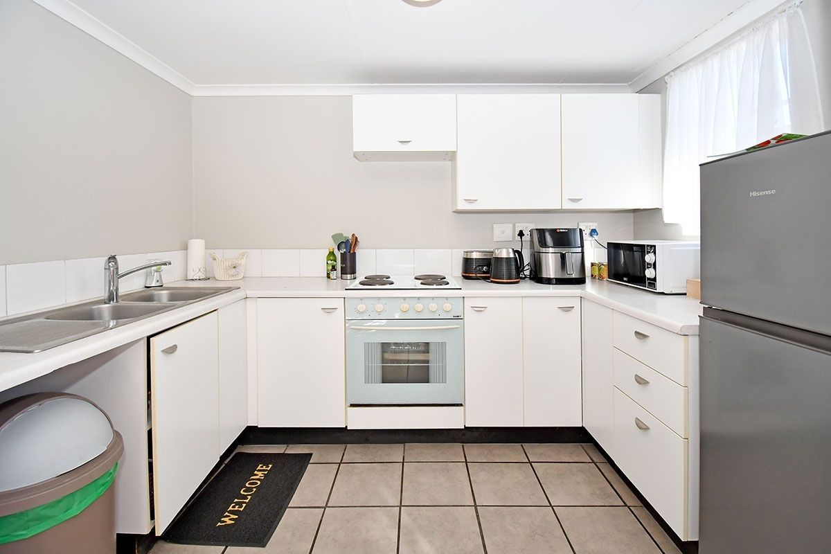A functional kitchen featuring white cabinetry, tiled flooring, a built-in oven and stove, and a double sink with a tiled backsplash.