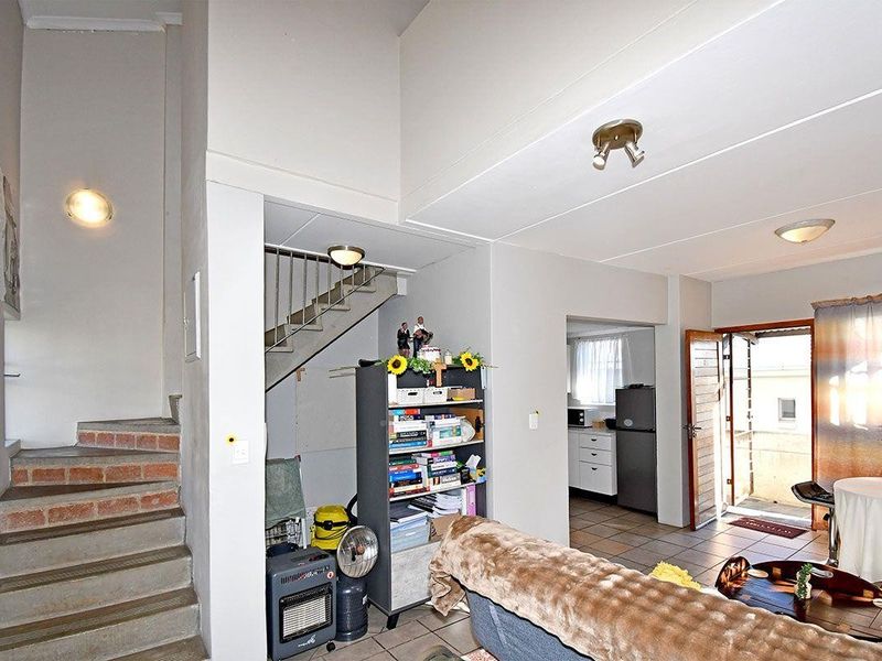 Open plan living area featuring a staircase with exposed brick risers, tiled flooring, and direct access to an outdoor space.