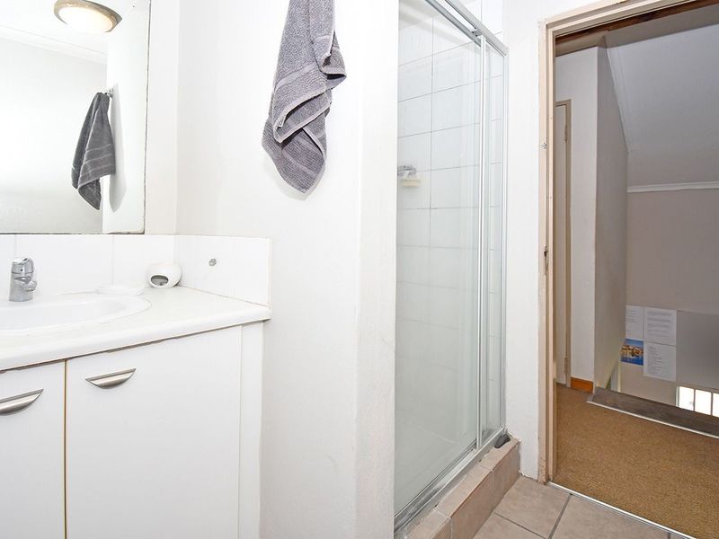 A functional bathroom featuring a vanity with basin, a shower enclosure with sliding glass doors, and tiled flooring.