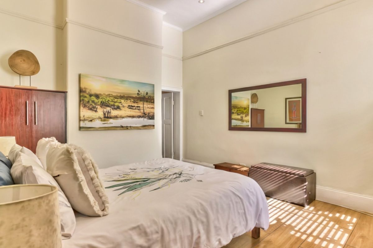 A well-maintained bedroom featuring timber-look floor tiles, high ceilings with picture rails, and recessed lighting.