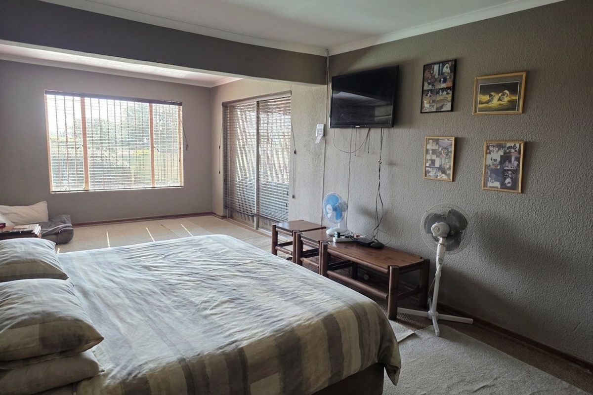 Spacious bedroom featuring textured walls, large windows with blinds, and a sliding glass door providing natural light and access to the exterior.