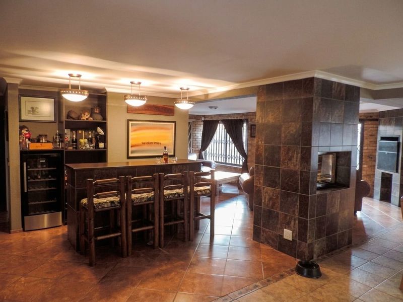 A well-appointed home bar area featuring a tiled counter, built-in shelving, and a central tiled fireplace, creating a cozy entertainment space.
