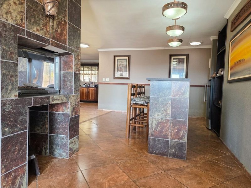 Open plan living area featuring a tiled floor, a prominent built-in fireplace with stone-look tiling, and a matching built-in bar counter.