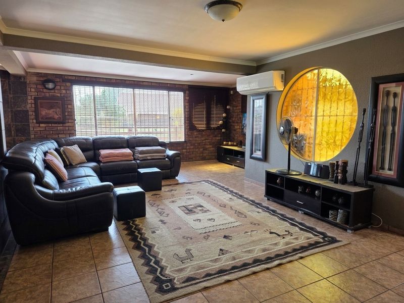 Spacious living room featuring exposed brick walls, tiled flooring, a unique circular feature window, and a wall-mounted air conditioning unit.