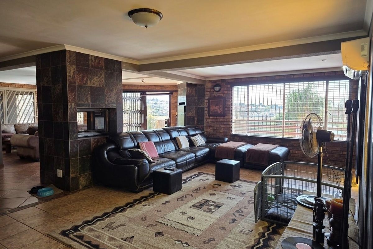 Spacious living room featuring exposed brick walls, a central tiled fireplace, and large windows with security gates, offering a comfortable and functional layout.