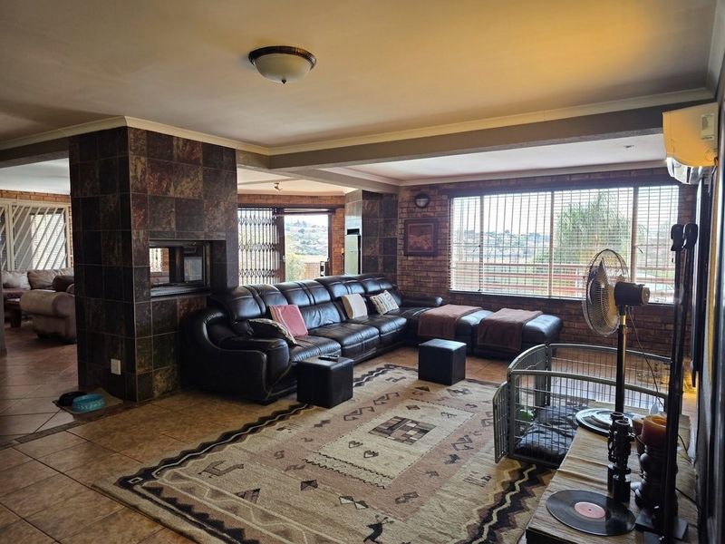 Spacious living room featuring exposed brick walls, a central tiled fireplace, and large windows with security gates, offering a comfortable and functional layout.