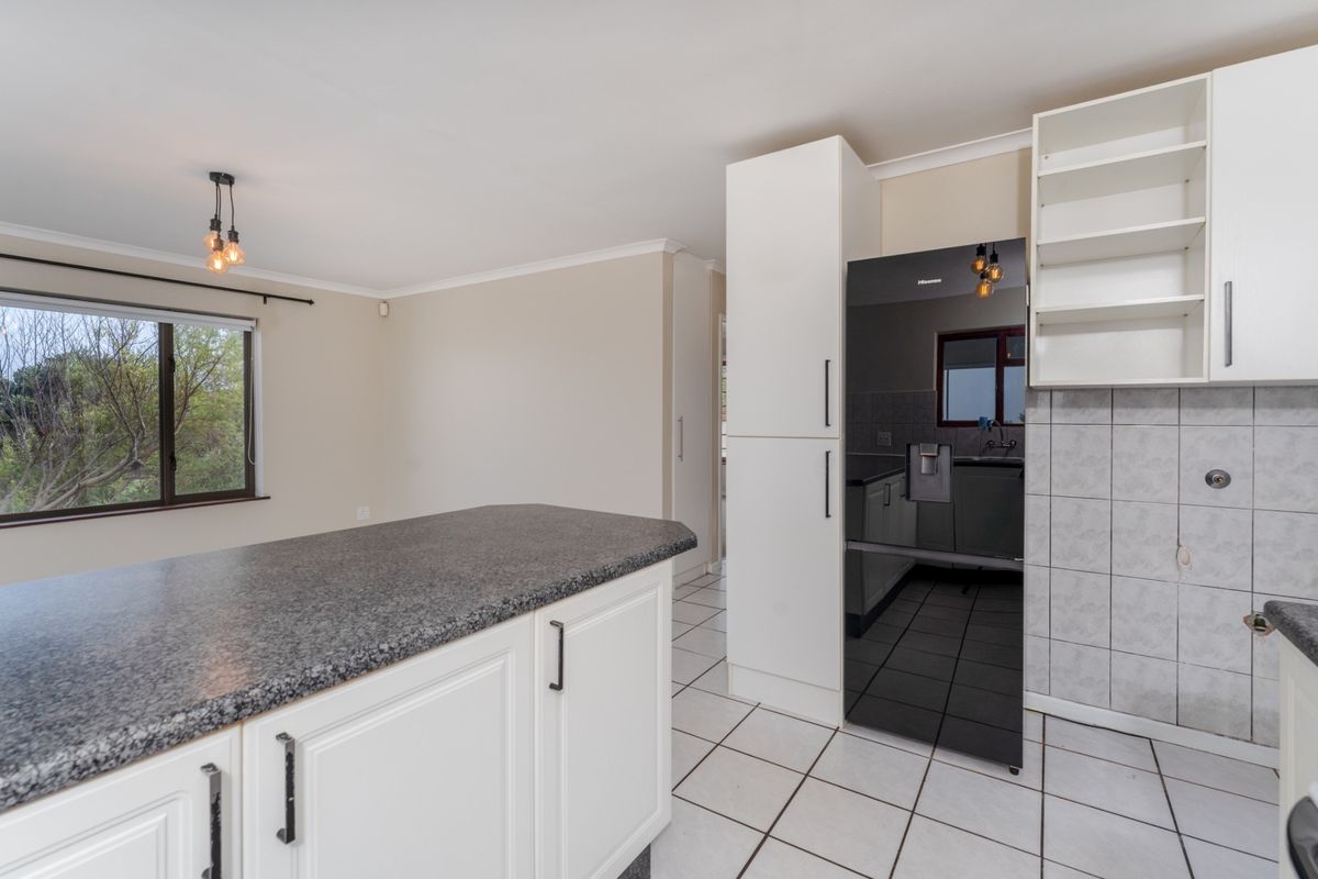 A functional kitchen featuring white cabinetry, granite countertops, tiled flooring, and a tiled backsplash, offering a clean and practical workspace.