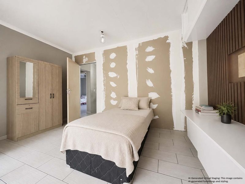 A bedroom featuring tiled flooring, a built-in wardrobe, and decorative wood wall paneling, currently requiring wall finishing and painting.