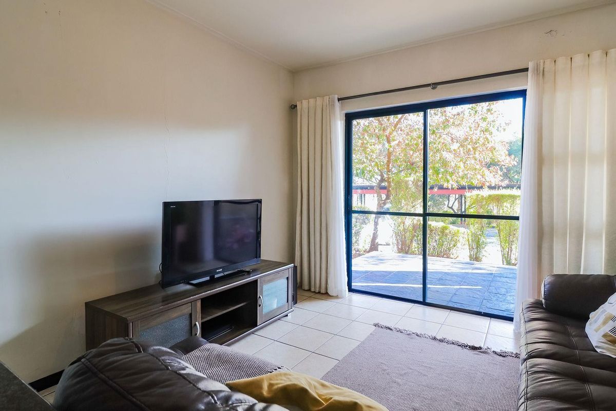 Living room featuring tiled flooring and a large sliding glass door providing access to an outdoor patio area.