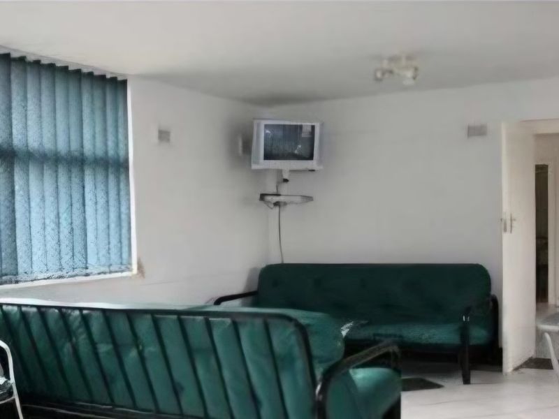 A living room area featuring vertical window blinds and a wall-mounted television bracket, requiring cosmetic updates to improve the overall aesthetic.