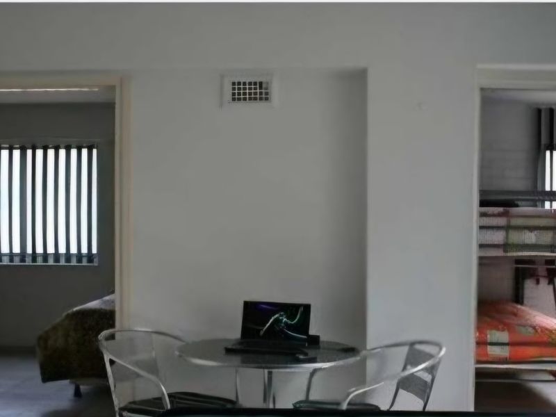 A central living area featuring a wall-mounted ventilation grille, providing access to adjacent bedrooms with security bars on the windows.