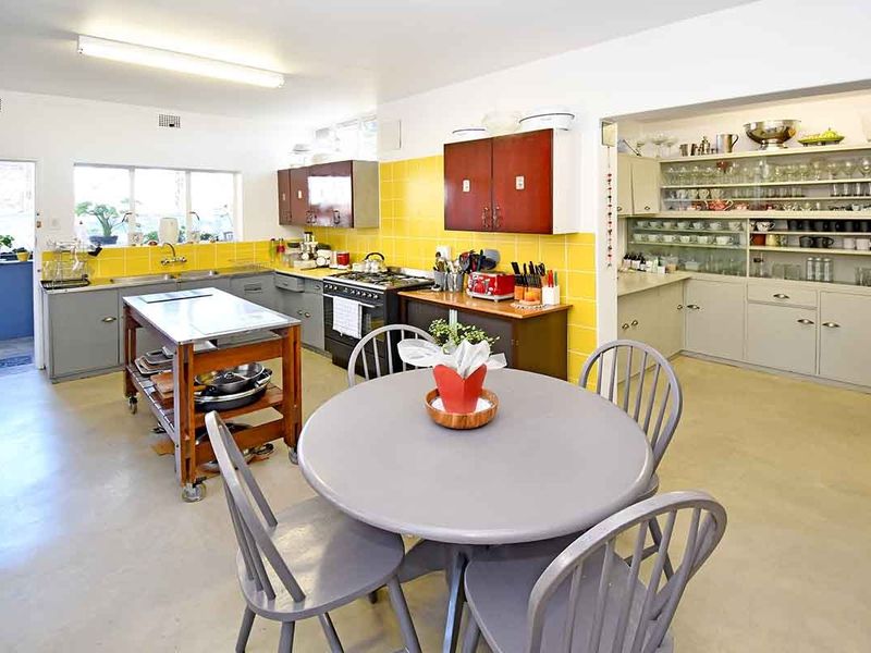 Spacious kitchen featuring yellow tiled backsplash, ample built-in cabinetry, gas stove, and a dedicated display shelving area for storage and organization.