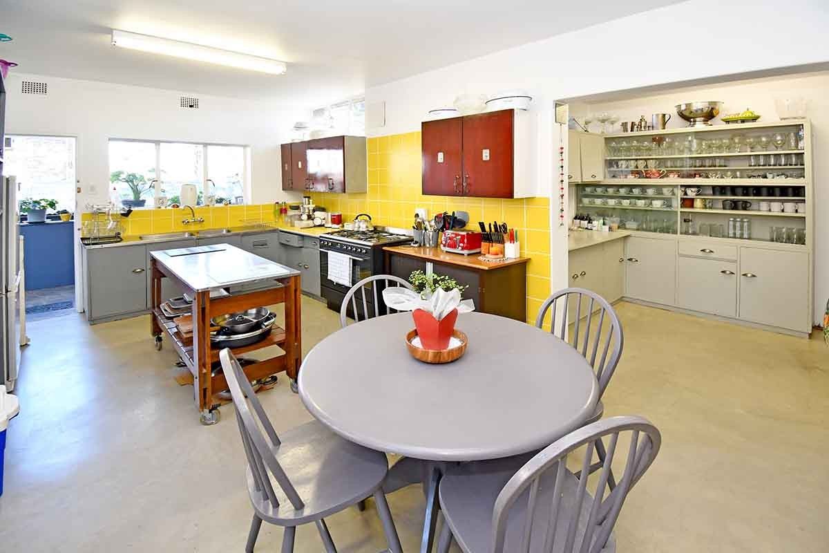 Spacious kitchen featuring yellow tiled backsplash, ample built-in cabinetry, gas stove, and a dedicated display shelving area for storage and organization.