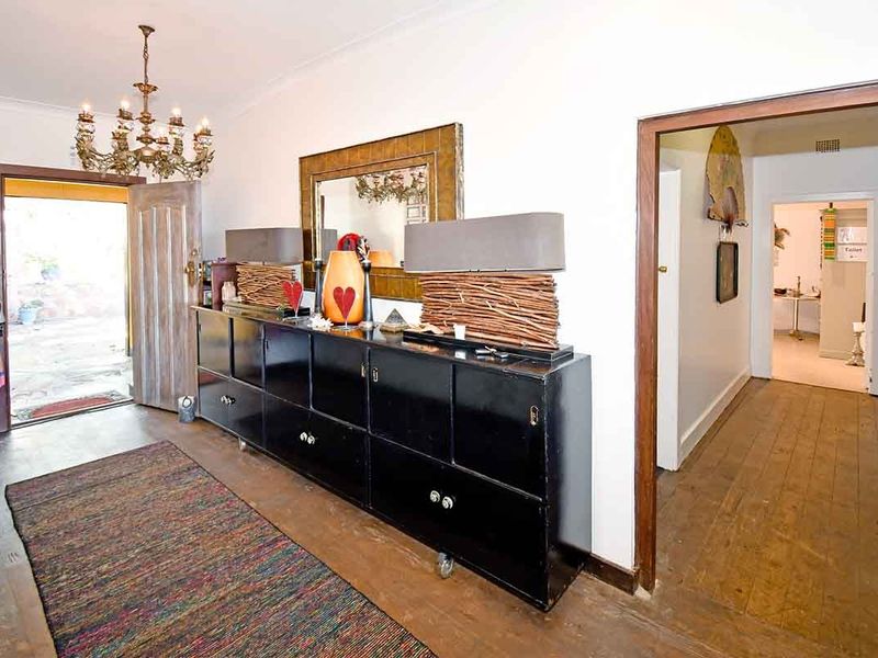 Entrance hall featuring original timber flooring, coved cornicing, and a classic chandelier, providing access to the main living areas and hallway.