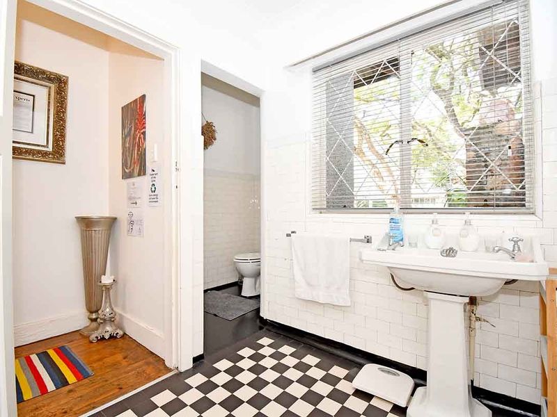 A classic bathroom featuring a pedestal sink, subway tile wall finishes, and a checkerboard tiled floor, with a separate toilet area visible.