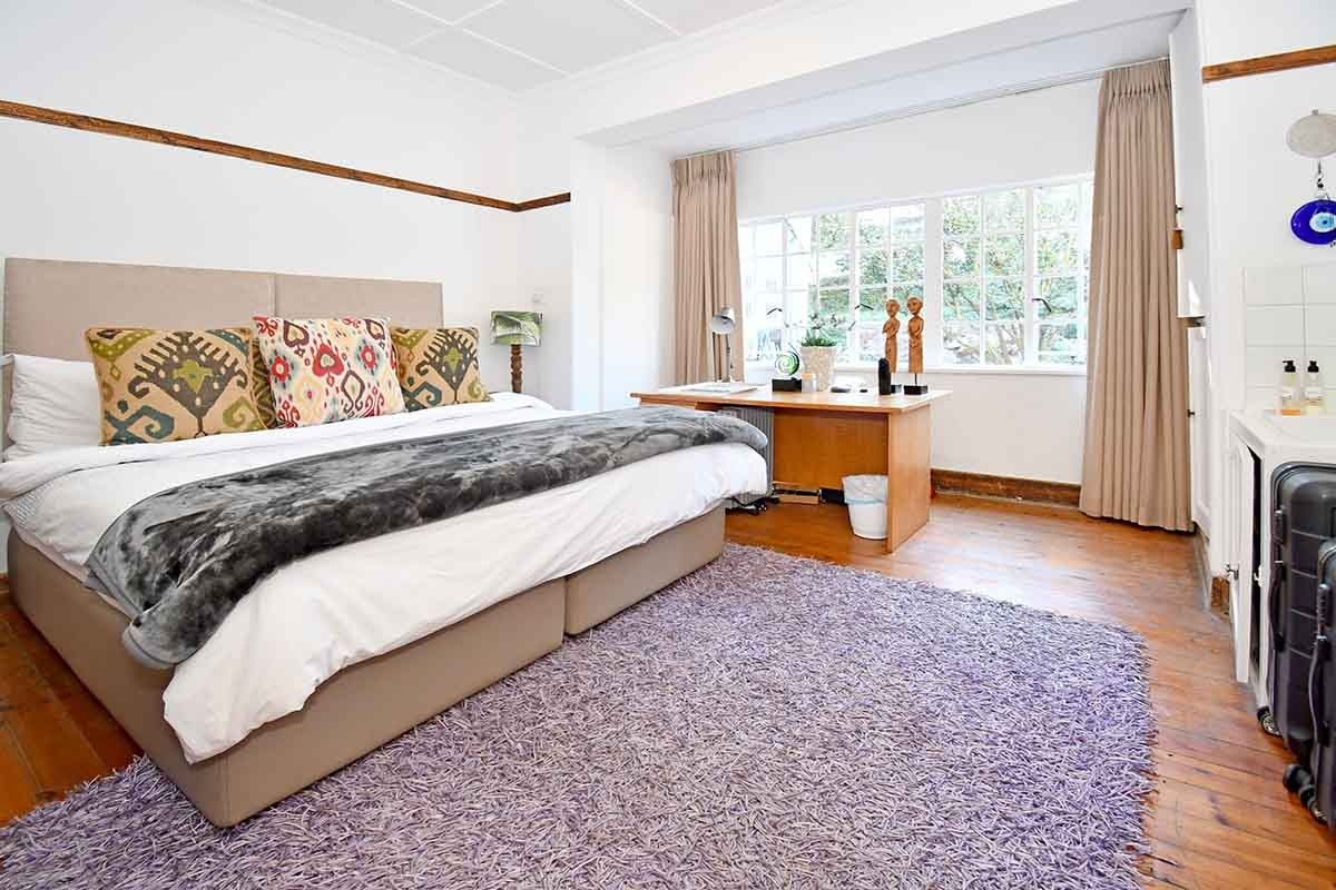 Spacious bedroom featuring original timber flooring, large multi-pane windows, and a convenient built-in basin area.