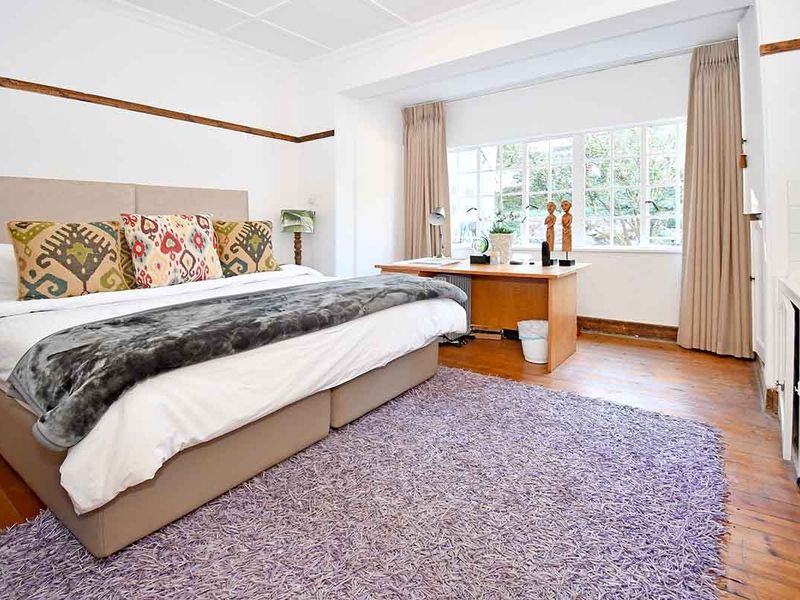 Spacious bedroom featuring original timber flooring, large multi-pane windows, and a convenient built-in basin area.