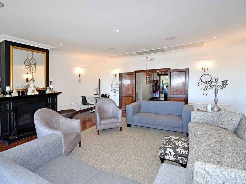 Spacious living room featuring a prominent black fireplace, hardwood flooring, elegant wall molding, and recessed lighting, providing a comfortable and well-defined seating area.