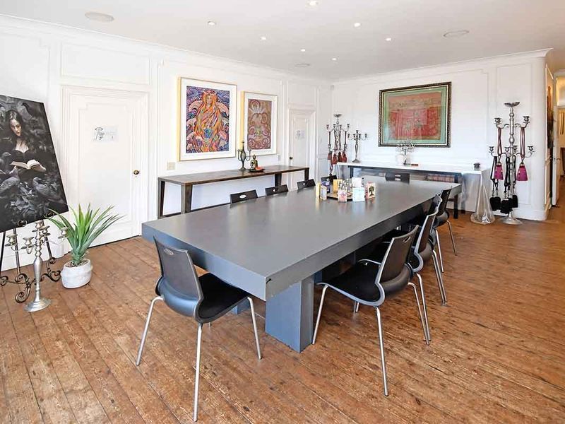 Spacious dining room featuring classic wainscoting, recessed ceiling lighting, and original hardwood flooring, offering a bright and versatile space for formal entertaining.
