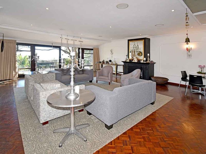 Spacious living room featuring classic parquet flooring, a central fireplace, and large sliding glass doors that provide ample natural light and outdoor access.