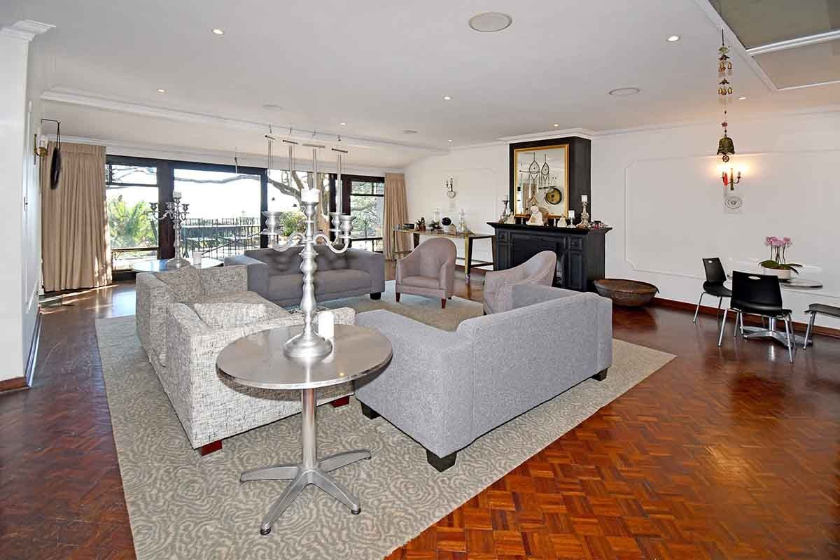 Spacious living room featuring classic parquet flooring, a central fireplace, and large sliding glass doors that provide ample natural light and outdoor access.