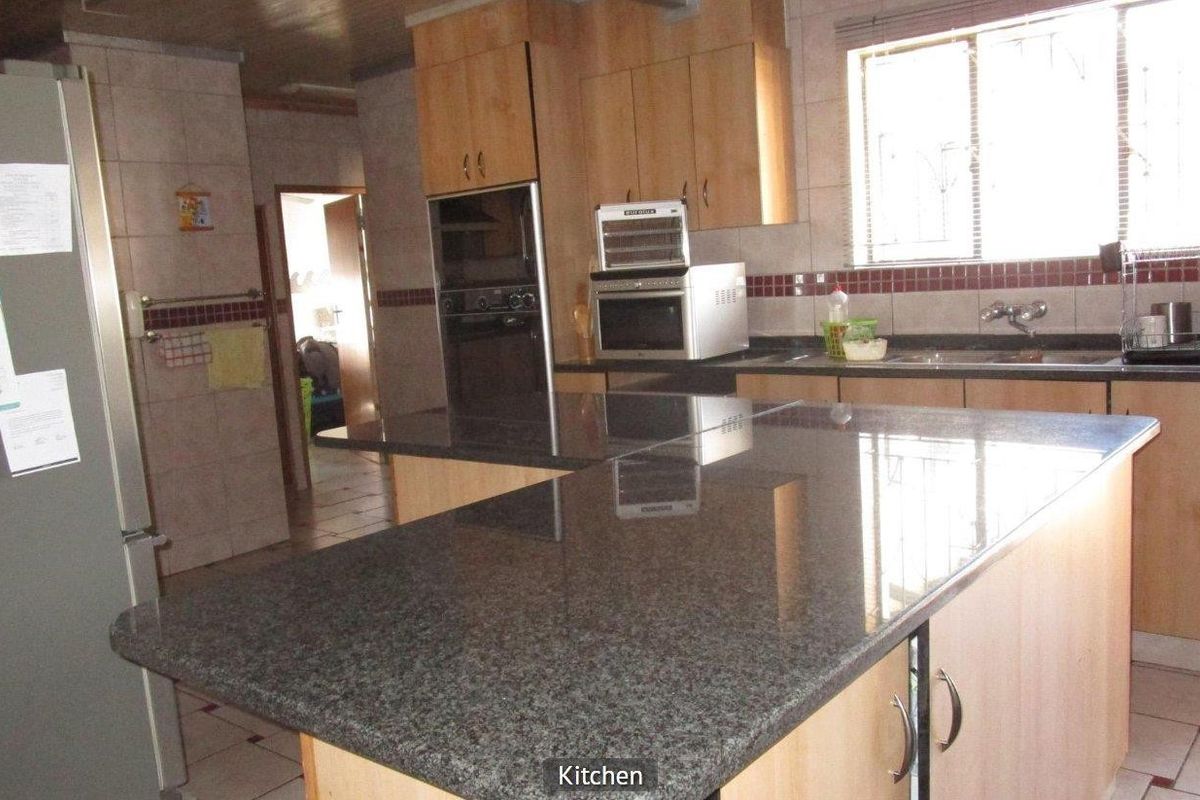 A functional kitchen featuring granite countertops, built-in cabinetry, and an integrated oven, offering a practical layout with tiled finishes throughout.