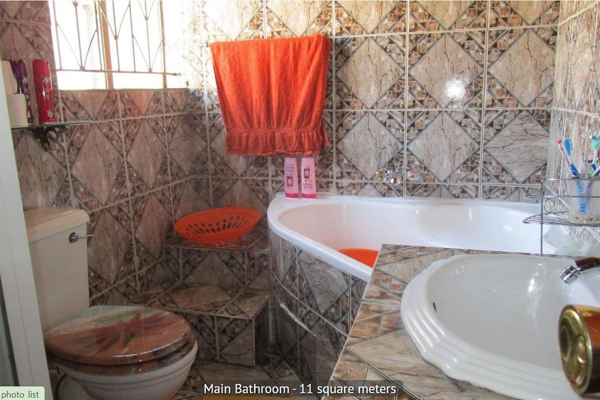 A bathroom featuring a corner bathtub, built-in vanity, and patterned ceramic wall tiles.