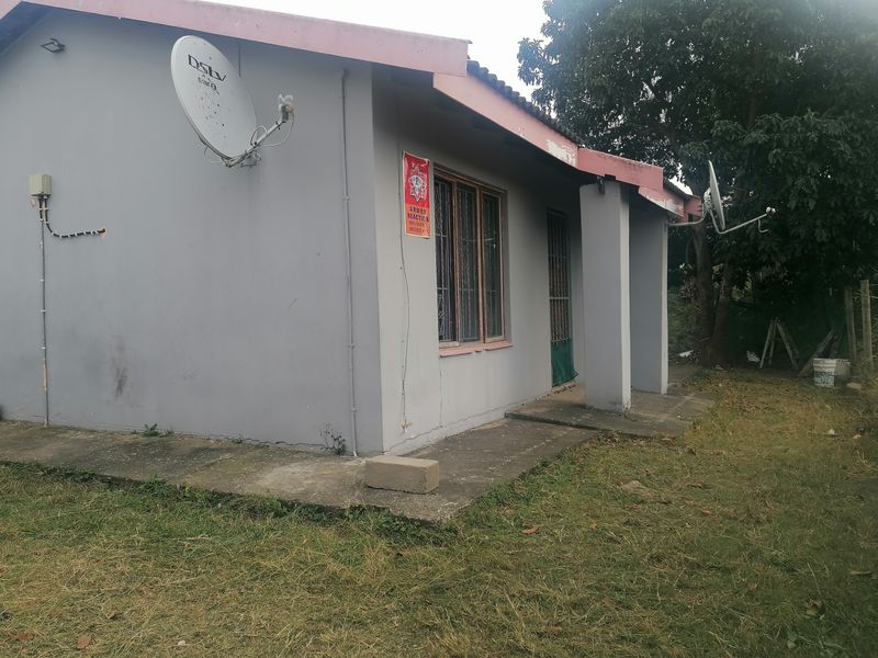 Rear exterior view of the house featuring a concrete patio, security bars on windows, and visible maintenance requirements on the walls and roof fascia.