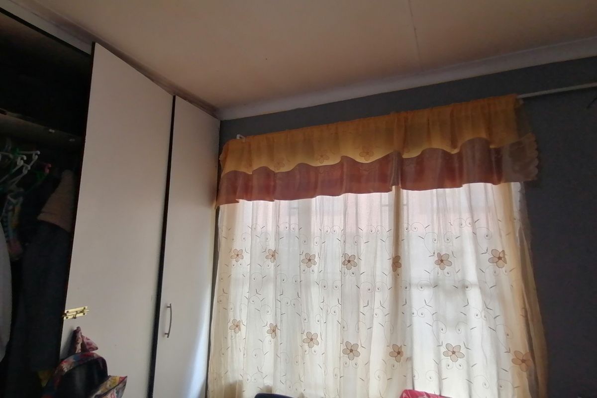 A bedroom featuring a built-in wardrobe and a window fitted with security bars.