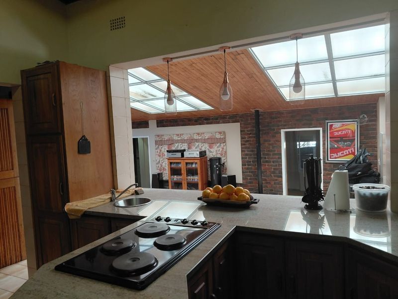 Open plan kitchen area featuring stone countertops, electric hob, built-in cabinetry, and a distinctive timber ceiling with skylights providing natural light.