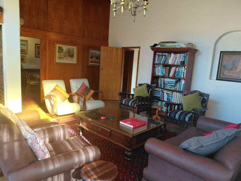 A living room featuring wood paneling, an arched doorway, and a classic chandelier, offering a traditional aesthetic with potential for modernization.