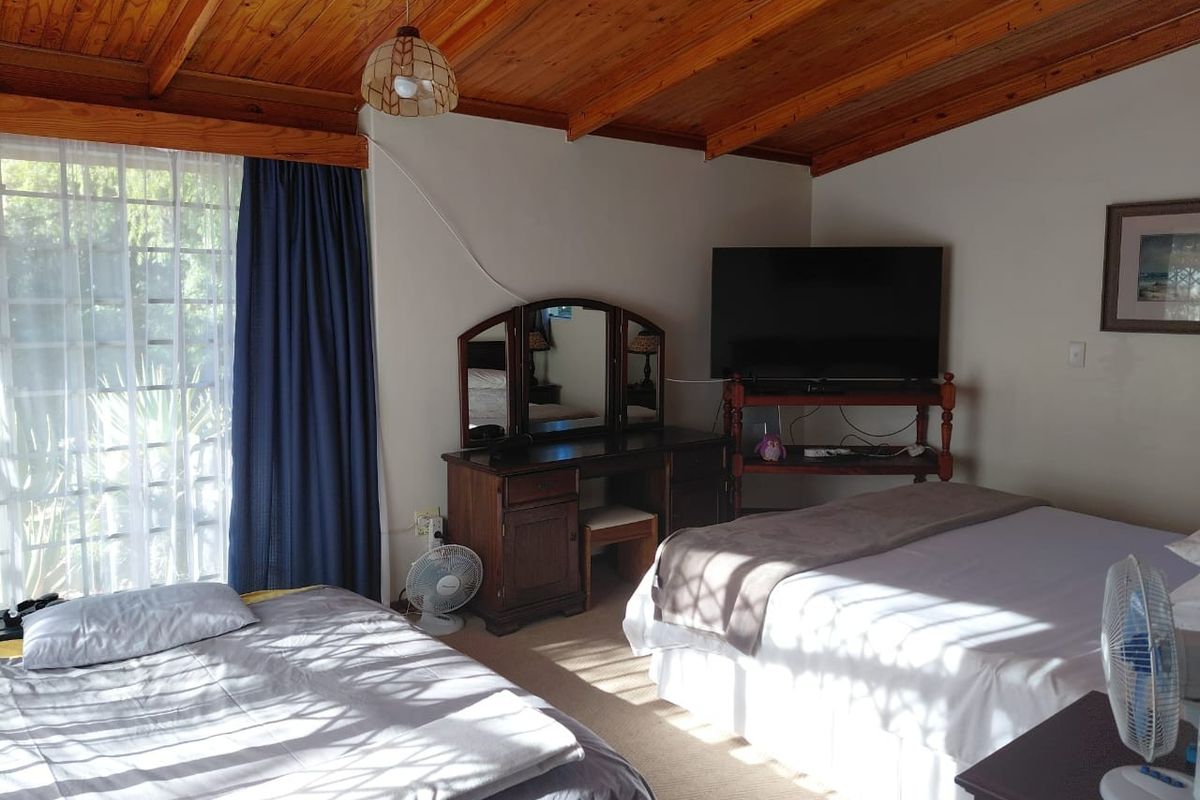 Spacious bedroom featuring a high exposed timber rafter ceiling, carpeted flooring, and direct access to the outdoors via a sliding glass door.