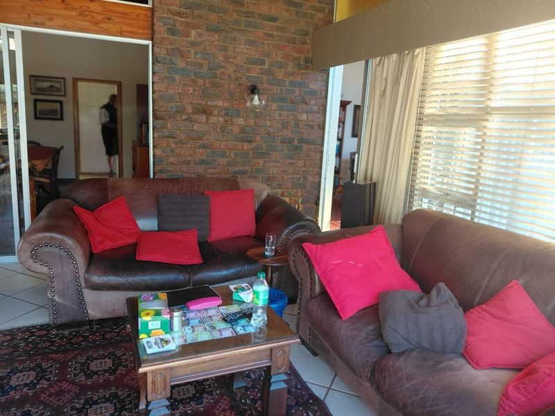 A living room featuring an exposed brick feature wall, tiled flooring, and large sliding glass doors that provide natural light.