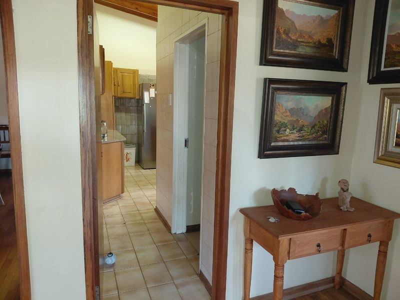 A view from a hallway looking into a kitchen area, featuring tiled flooring and traditional wooden door frames.