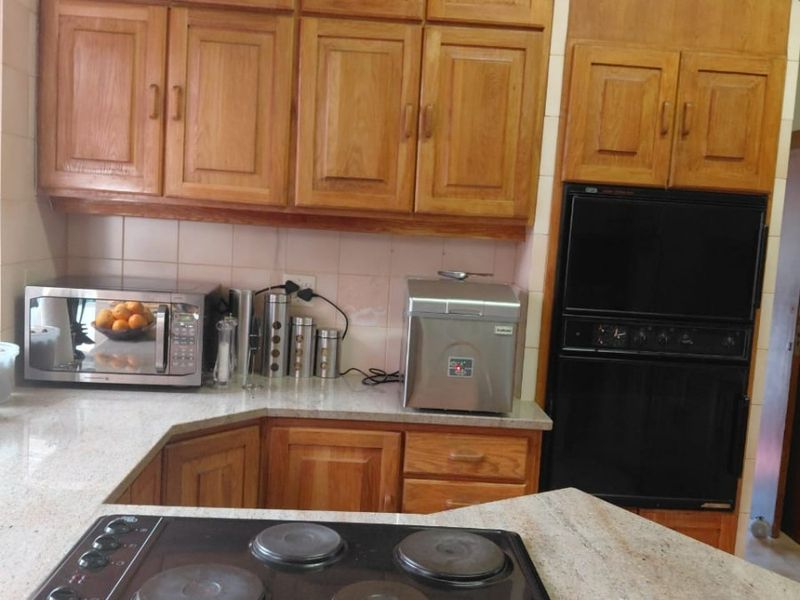 A functional kitchen featuring traditional wooden cabinetry, stone countertops, a built-in double oven, and an integrated electric hob.