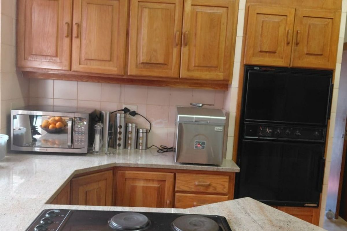 A functional kitchen featuring traditional wooden cabinetry, stone countertops, a built-in double oven, and an integrated electric hob.