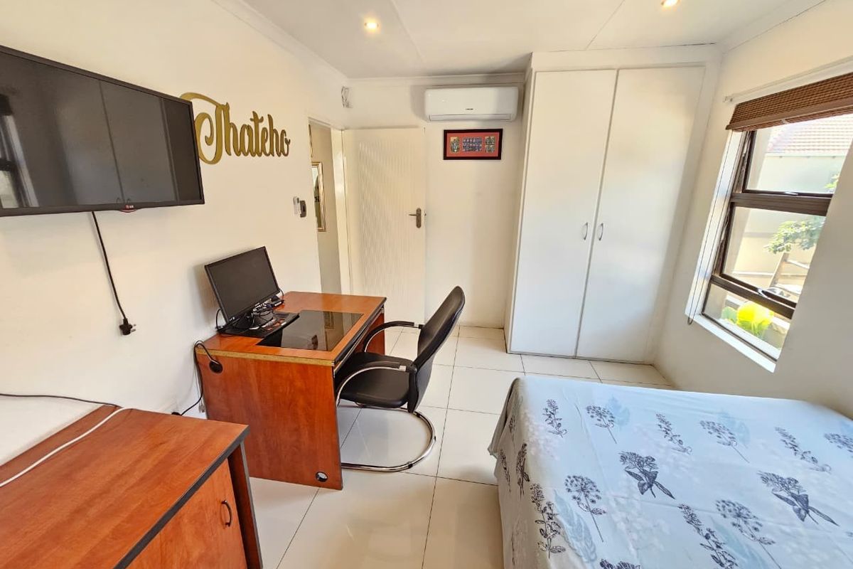 A functional bedroom featuring tiled flooring, built-in cupboards, and a wall-mounted air conditioning unit, providing a comfortable and practical living space.