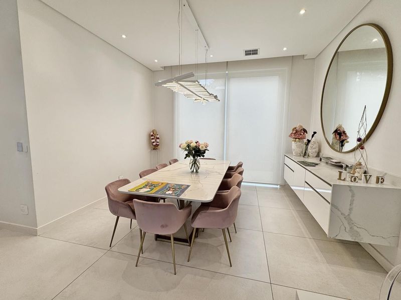 Modern dining room featuring large format floor tiles, a sleek wall-mounted floating sideboard with stone top, and contemporary recessed and pendant lighting.