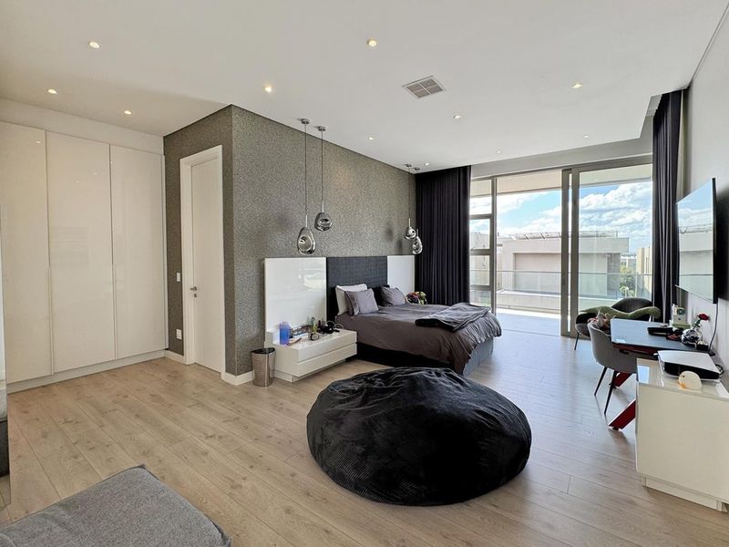 Modern bedroom featuring laminate flooring, built-in cupboards, a textured feature wall, and large sliding doors opening onto a private balcony.