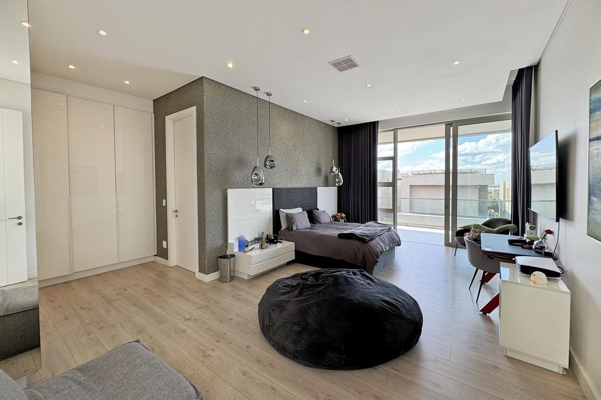 Modern bedroom featuring laminate flooring, built-in cupboards, a textured feature wall, and large sliding doors opening onto a private balcony.