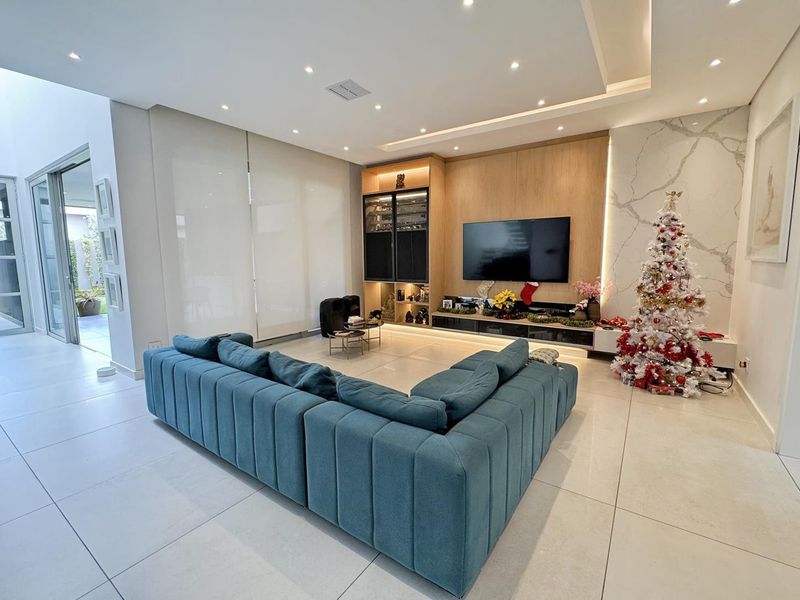 Modern living room featuring a built-in media unit, marble-look feature wall, recessed ceiling lighting, and large sliding glass doors leading to the exterior.