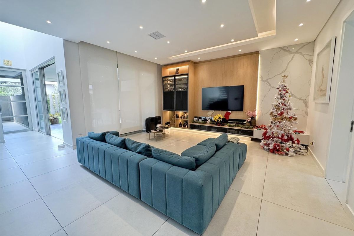 Modern living room featuring a built-in media unit, marble-look feature wall, recessed ceiling lighting, and large sliding glass doors leading to the exterior.