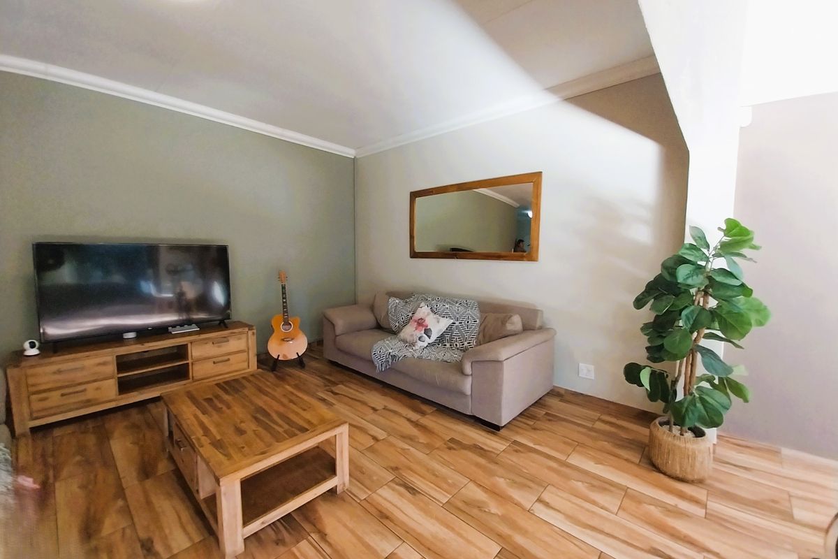 A well-maintained living room featuring wood-look tile flooring and clean, neutral wall finishes, providing a comfortable and inviting space.