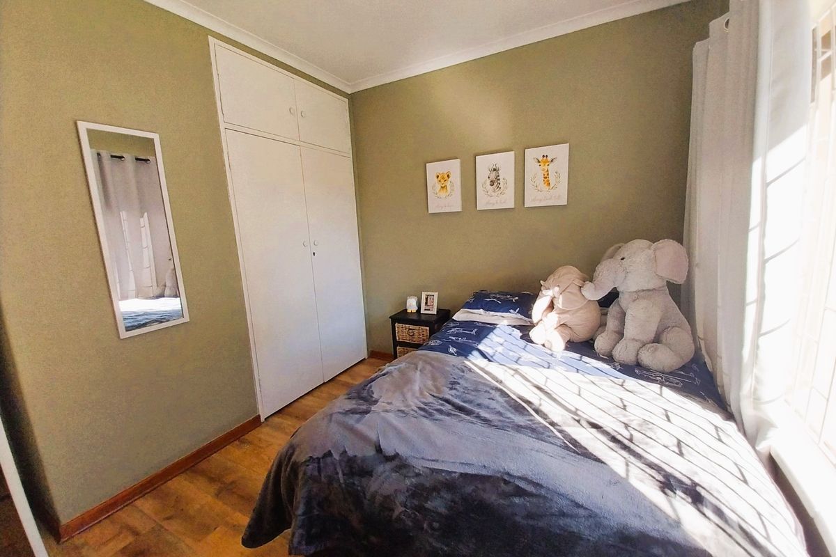 A cozy bedroom featuring laminate flooring, built-in cupboards, and natural light, providing a comfortable and functional living space.