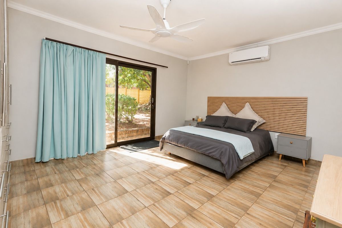 Spacious bedroom featuring tiled flooring, a built-in wardrobe, ceiling fan, split-system air conditioning, and direct access to the garden through a sliding glass door.